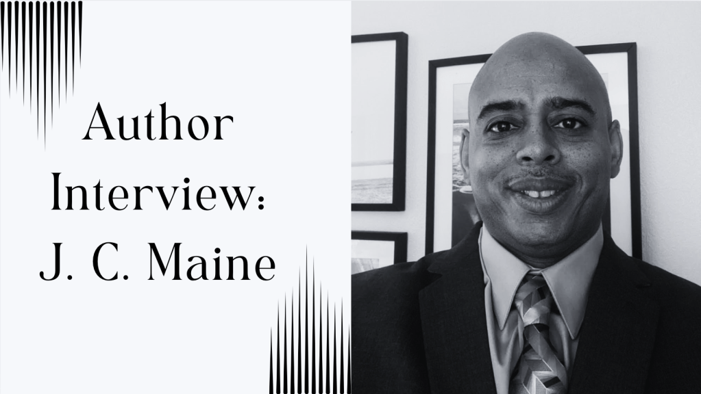 picture of author standing in front of a wall of framed photos. author is wearing a suit with tie. text says, author interview: J. C. Maine