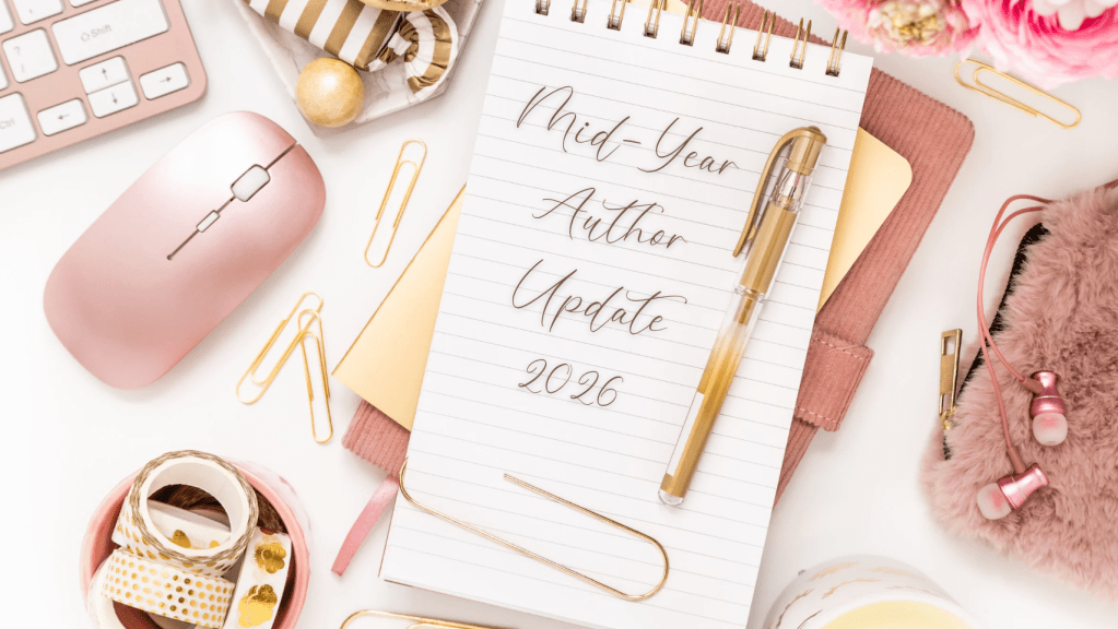 Flat lay blog header image featuring a pink-and-gold workspace. A spiral notebook in the center reads “Mid-Year Author Update 2026” in elegant script. Surrounding the notebook are a pink computer mouse, keyboard, gold pen, paper clips, decorative tape, flowers, earbuds, and a fuzzy pink pouch, creating a feminine and organized writing-themed aesthetic.